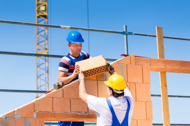 Robotnicy układają cegły, budowa domu